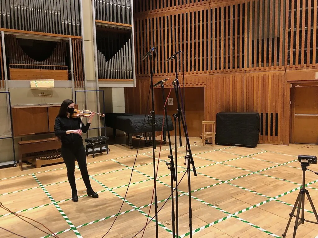 Violinist performing in the Sir Jack Lyons Concert Hall with stereo microphone pairs on stands