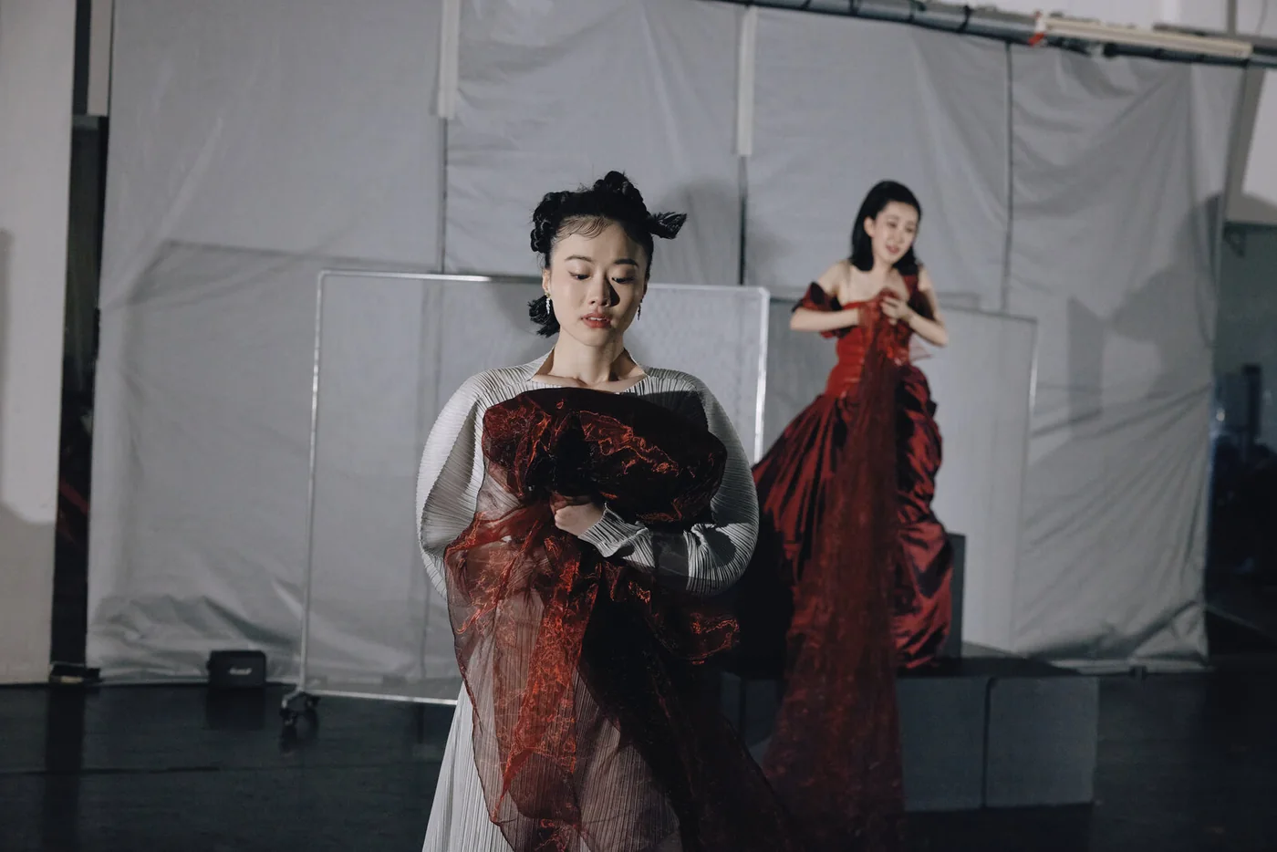 Reincarnated as a Convenience Store: two performers in red and dark gowns on stage